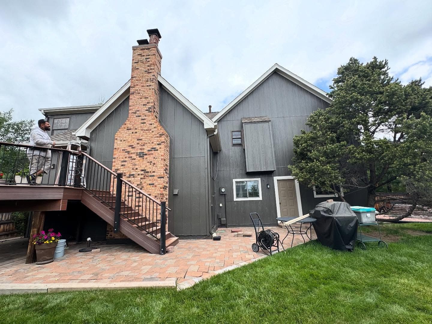 Gray siding home with brick chimney and new deck